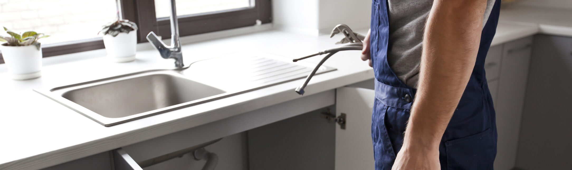 Plumber fixing a broken sink in a kitchen